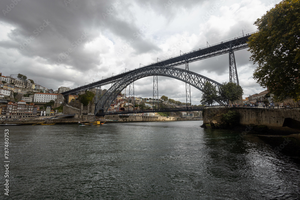 Luis I Bridge from the west side from the river level - storm clouds - yellow boat for transporting barrels
