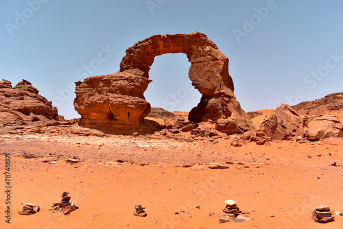 A natural rock formation in the shape of an arch in the Sahara, a weathered orange rock in Tassili N'Ajjer National Park, Tadrart Rouge, Algeria. photo