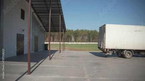 Transportation truck driving backward to arrive at a production factory. White transport truck arriving to the storage facility. The goods transport truck arrives to the manufacturing plant.