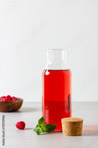 Raspberry drink in the glass bottle on the light background.