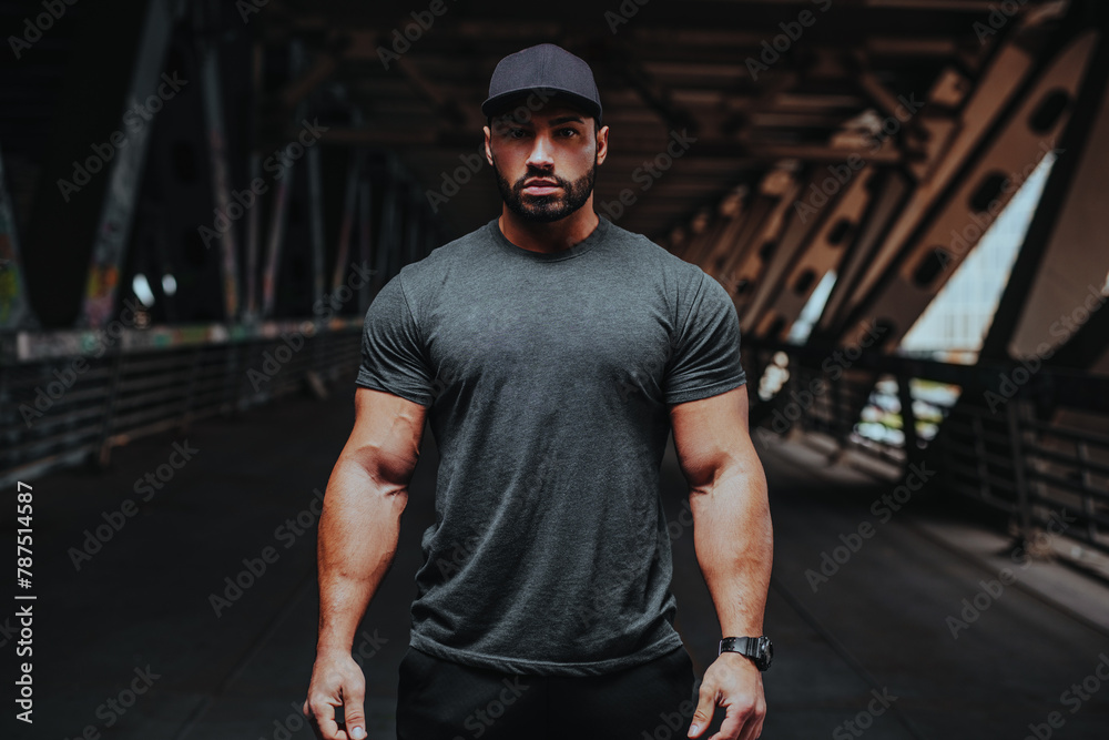 Obraz premium Young strong man bodybuilder posing on urban background