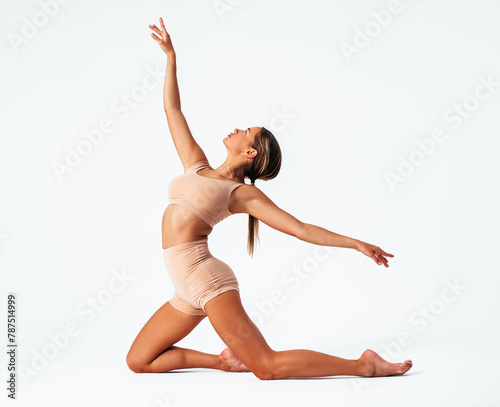Young woman gymnast stretching on white background