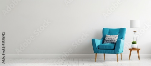 Simple room with a blue armchair, side table, and white lamp. © Vusal