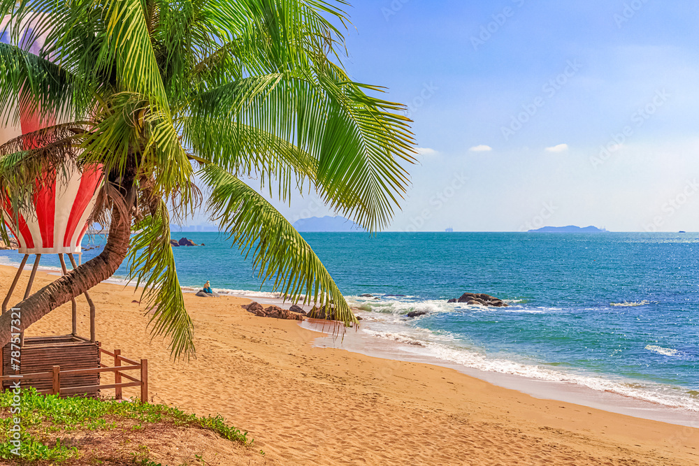 Fototapeta premium View of the shore of the South China Sea with a sandy beach, palm trees and a hot air balloon, China