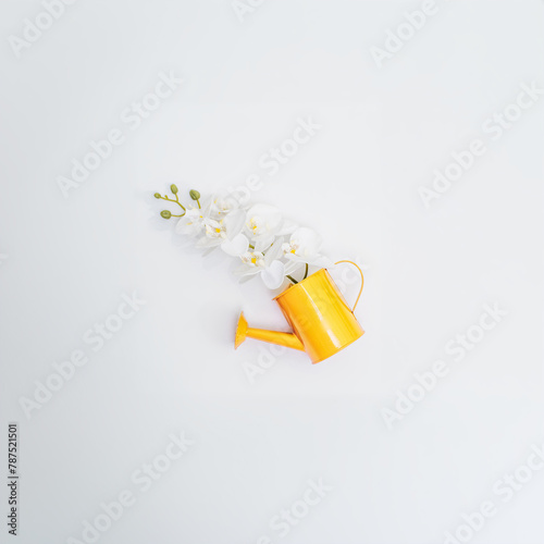 A yellow watering can with an orchid inside. Top view, spring and gardening concept.