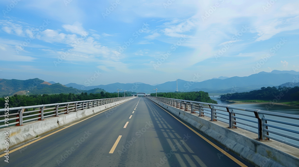 A long road bridge over the river with views of the mountains in the distance. Asphalt highway.