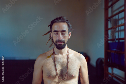 head shot portrait shirtless latin American yogui sitting practicing Hata yoga meditating eyes closed  indoors	