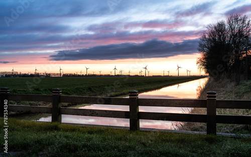 River enclosed by wooden fence with sunset sky and clouds in the background