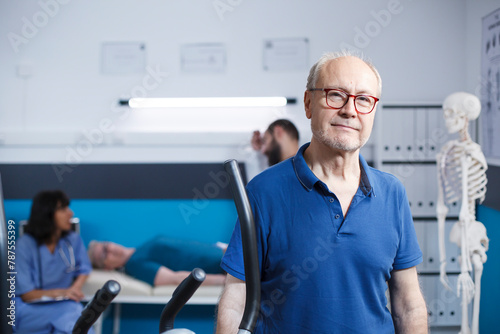Portrait of retired patient visiting physical therapy center. Senior old man looking at the camera, preparing to recover via exercise and fitness at a rehabilitation treatment clinic.
