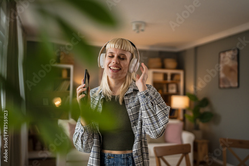 Young woman with headphones listen music and sign on mobile phone happy