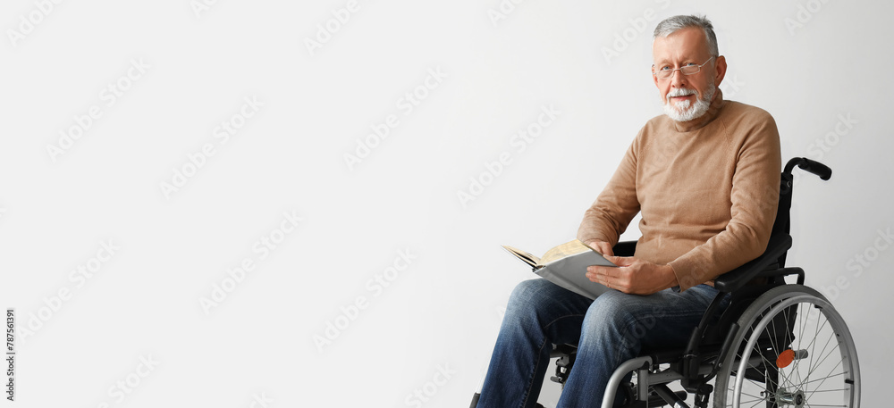 Senior man in wheelchair reading book on light background Senior man in wheelchair reading book on light background