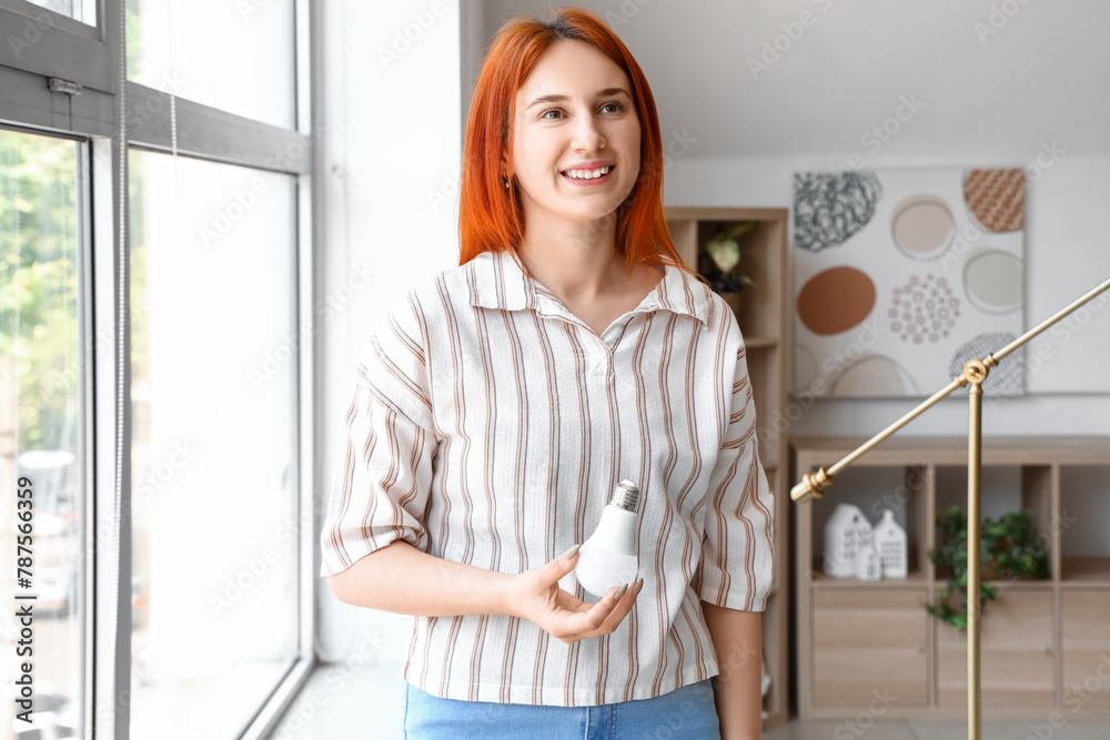 Pretty young woman holding light bulb at home Pretty young woman holding light bulb at home