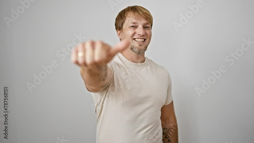 A cheerful caucasian man with tattoos smiling and gesturing thumbs up against a white background photo