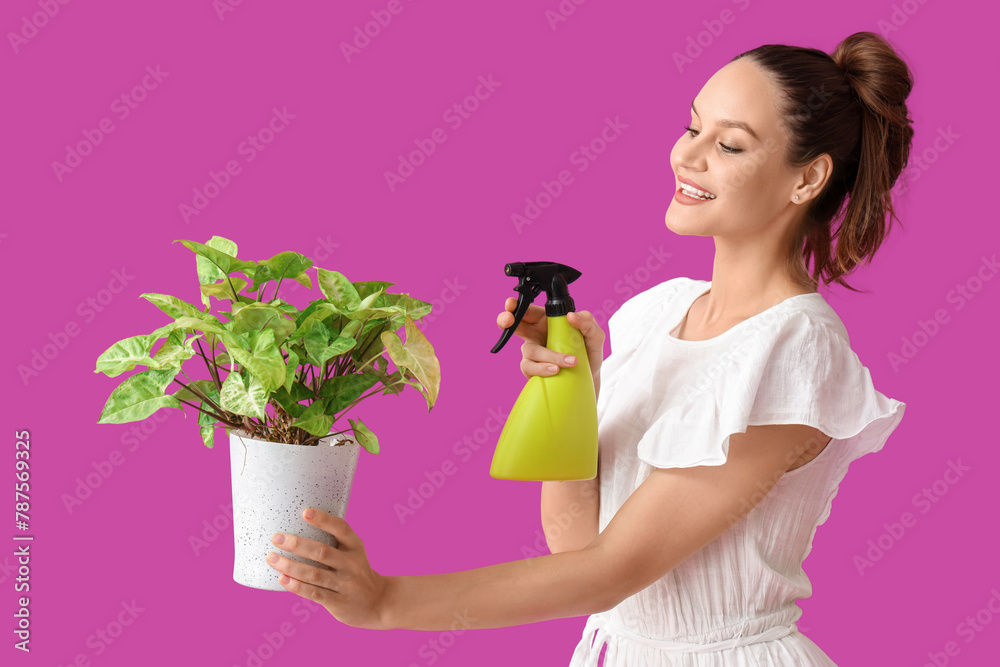 Young woman with houseplant and spray bottle on purple background Young woman with houseplant and spray bottle on purple background