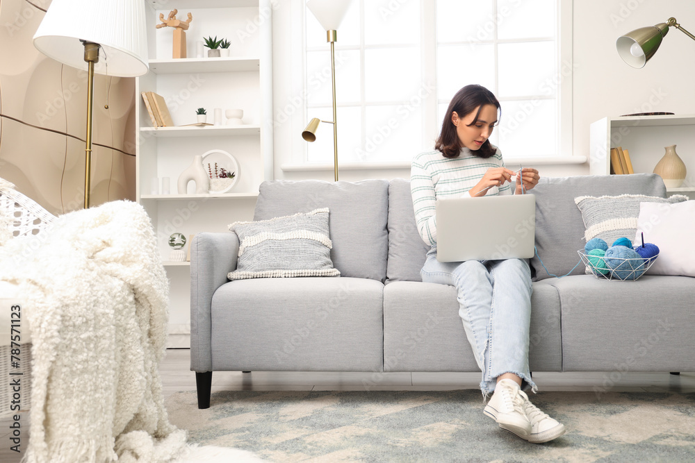 Young woman knitting with needles and laptop at home Young woman knitting with needles and laptop at home