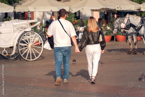 A Gen Z couple in love walks hand in hand through a sun-drenched city square amid pigeons and horse-drawn carriages, capturing the essence of urban romance and the timeless charm historic architecture