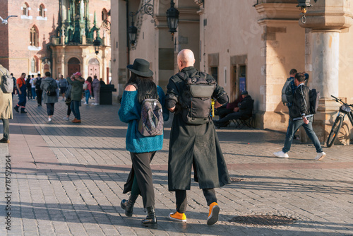 Exploring the city in 2024: A bald man in a coat and a woman in a hat with backpacks walk together in the old city, representing the trend of everyday urban tourism and socializing
