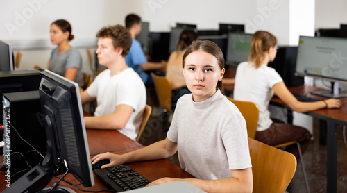 Portrait of girl student looking at camera during lesson in computer class in college