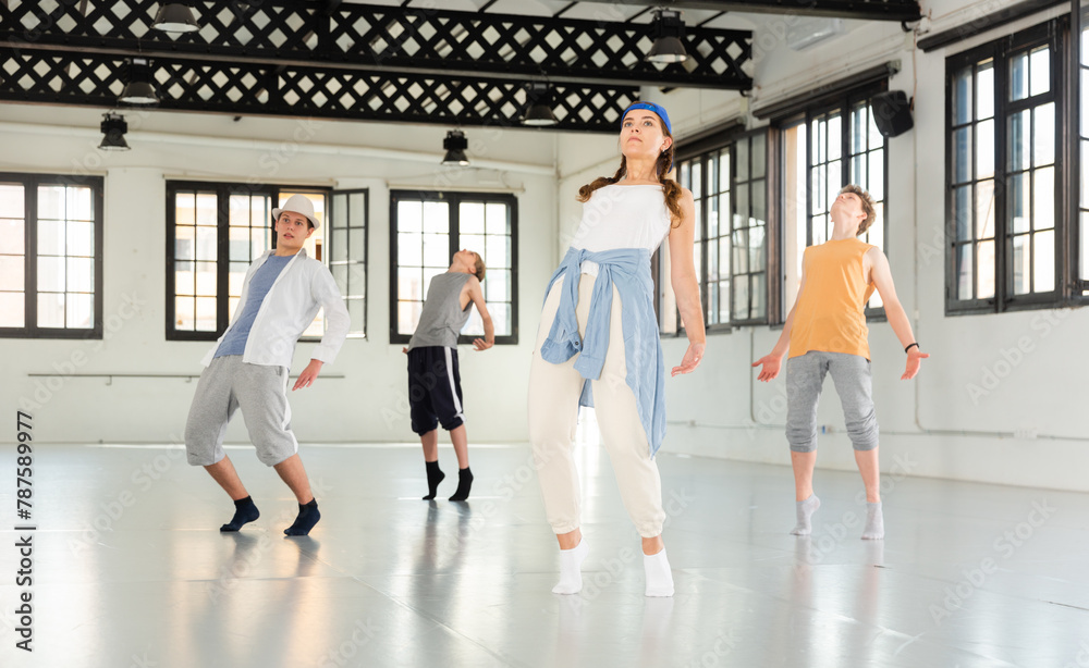 Fototapeta premium Teenager girl and boys exercising hip-hop dancing indoors