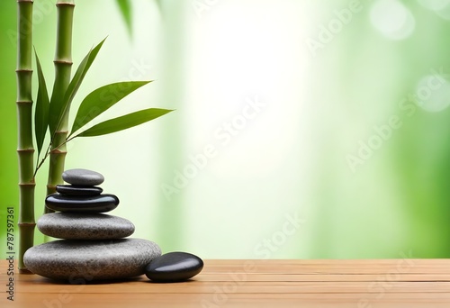 Stack of smooth stones with bamboo leaves on a wooden surface against a soft green background