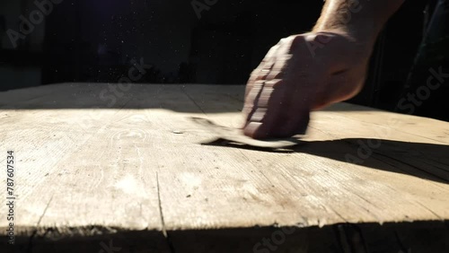 hand sands wooden boards in the suns rays. sanding wood. Processing wood with sandpaper.movement of dust in the suns rays.Wood surface treatment process. 4k footage photo