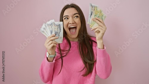 Happy woman holding peruvian soles and us dollars against a pink background, portraying wealth and excitement. photo