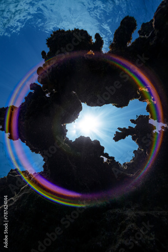 Fototapeta Naklejka Na Ścianę i Meble -  A full-circle rainbow is created in this image when the sunburst seen through an opening in the coral reef hits the dome port of the camera.