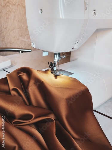 Slika na platnu The image shows a close-up of a sewing machine stitching brown silk fabric