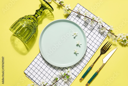 Beautiful table setting with blossoming branches on yellow background © Pixel-Shot