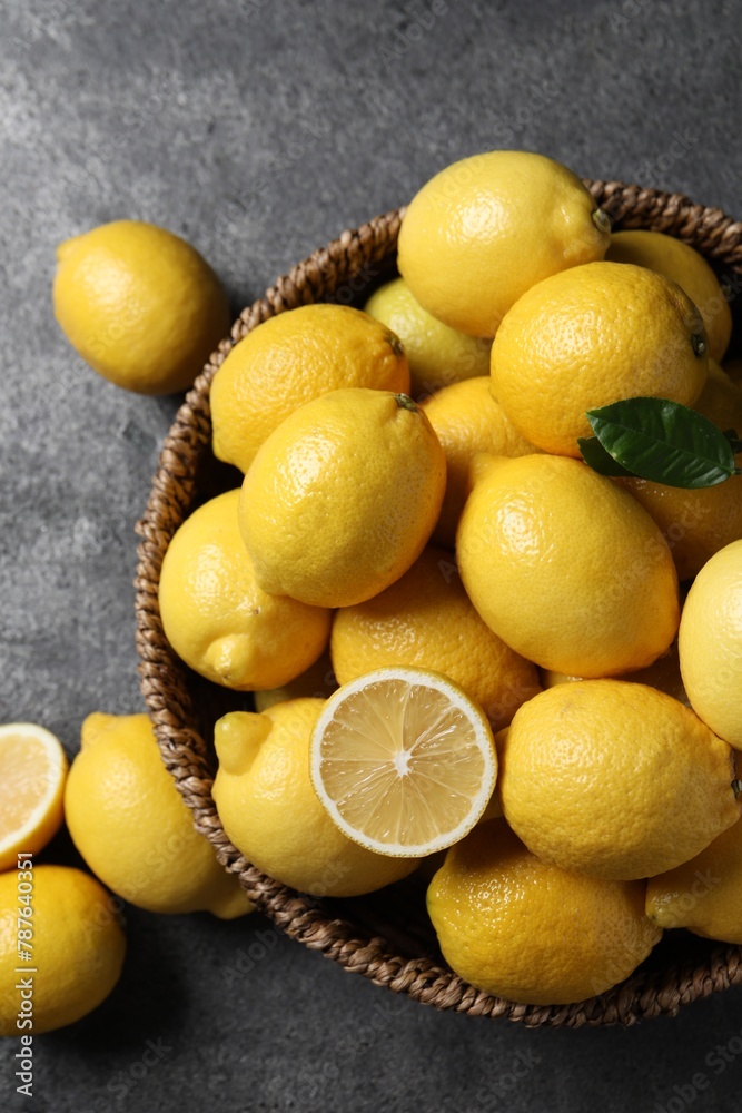 Fresh lemons in wicker basket on grey table, top view