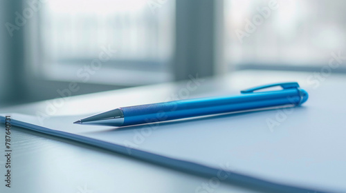 A vibrant blue ballpoint pen resting on a clean white desk, inviting words to be written. photo