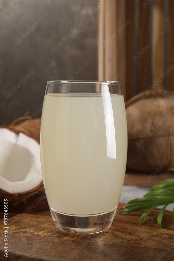 Glass of coconut water, palm leaf and nuts on grey table Glass of coconut water, palm leaf and nuts on grey table