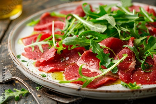 white plate with beef carpaccio and arugula