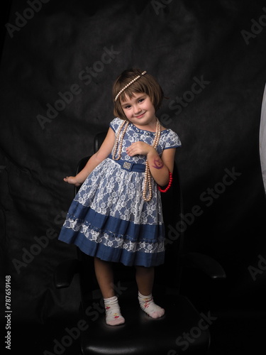 little girl in a blue dress on a black background in the studio in full growth (ID: 787659148)
