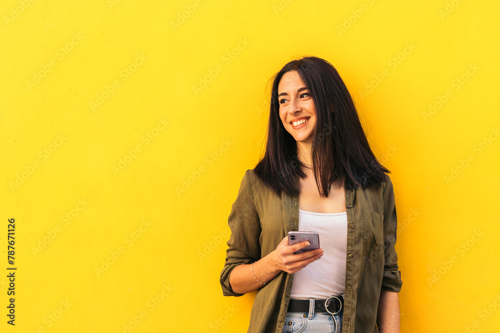 young stylish woman using her mobile and looking aside young stylish woman using her mobile and looking aside