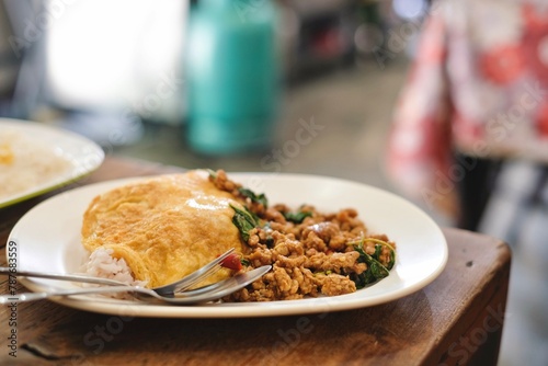 A plate of pad kra pao (holy basil pork mince stir-fry) with omelette and mixed grain rice at a street food stall near the Grand Palace in Phra Nakhon, Bangkok, Thailand