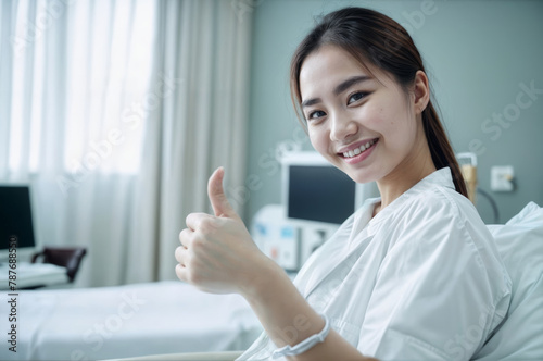 Young asian female patient smile and show thumb up in hospital room