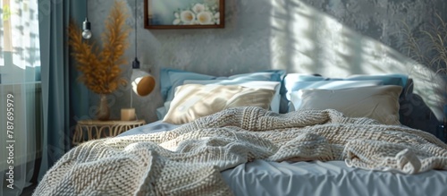 A knitted blanket is spread on a king-size bed in a cozy bedroom with a contemporary design, featuring soft gray and blue tones.