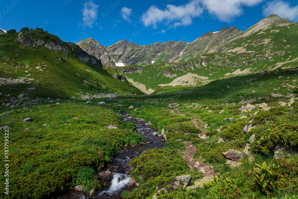 The valley of the Malaya Dukka River on the slopes of the Arkasar ridge in the North Caucasus and the tourist trail to the Dukka Lakes on a sunny summer day, Arkhyz, Karachay-Cherkessia, Russia