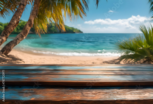 Tropical beach view from a wooden table, featuring clear blue waters, sandy shore, and lush palm trees.