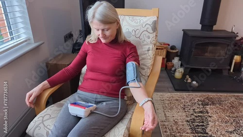 Middle aged woman taking her own blood pressure at home,using a digital self-monitor kit,Worcester,United Kingdom.