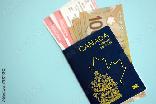 Canadian passport with money and airline tickets on blue background close up. Tourism and travel concept