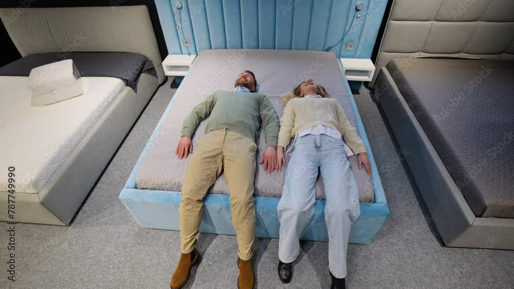 A man and woman lying on bed testing mattress in furniture store