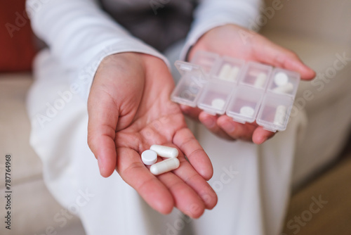 Closeup image of a woman holding pills and pillbox