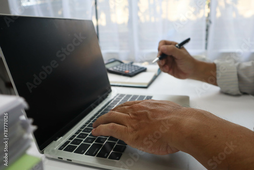 businessman hands searching for data on Notebook with analyzing charts at his workplace.