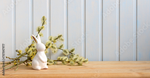 Easter long background with a rabbit figurine and willow branches. Easter background, spring holiday backdrop.