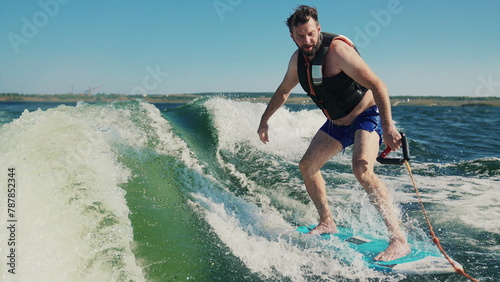 A man learns to wakesurf behind a boat. Fun on the water during the hot summer on the lake.