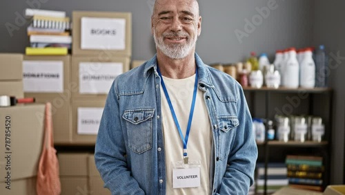 Mature man volunteering at a food bank organizing donations indoors photo