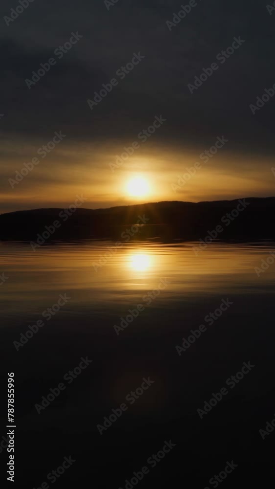 Beautiful landscape view of the forest lake at sunset. Reflection of the sun and sky on the surface of the water. A calm natural scene. Vertical video, shorts. Beautiful landscape view of the forest lake at sunset. Reflection of the sun and sky on the surface of the water. A calm natural scene. Vertical video, shorts.