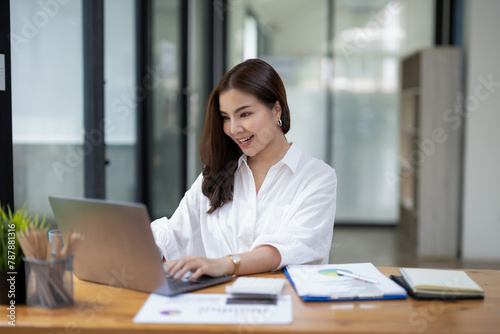 Joyful businesswoman with a victorious gesture, celebrating success while working on her laptop in a sunny office space.